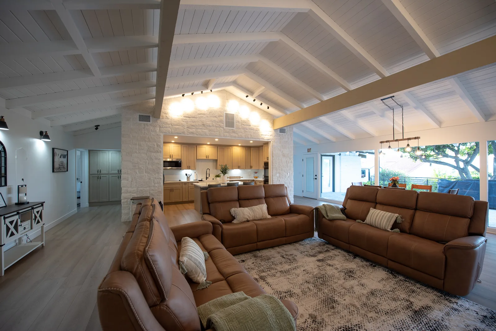 Open-concept living area with stone accent wall and vaulted wood-beam ceiling at Ohana Excellence Crown Ranch, Corona, California
