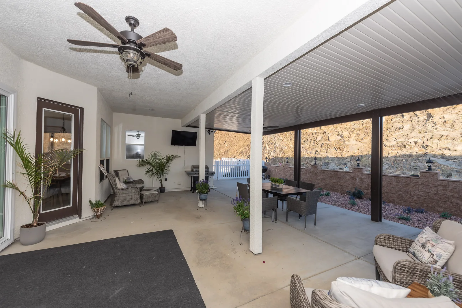 Covered outdoor patio with a dining table and seating at Manitou Home in Corona, California